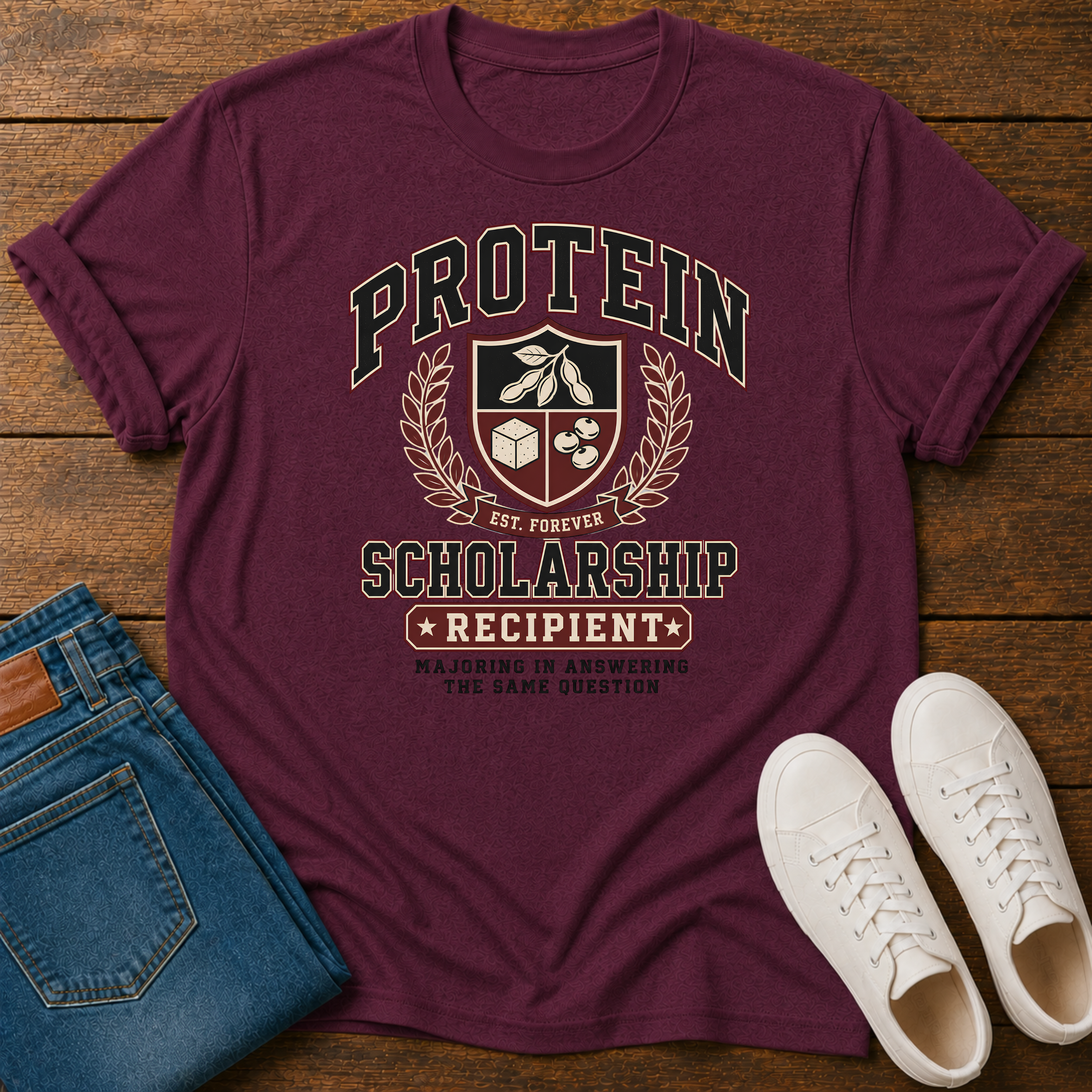 maroon t-shirt with Vintage collegiate crest design reading “Protein Scholarship Recipient” with soybean, tofu, and bean illustrations and the words “Majoring in Answering the Same Question.”