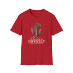 Red short-sleeve crewneck t-shirt featuring a graphic of a cactus with a flower and the text 'I'D RATHER BE DIFFICULT THAN EASY TO USE' printed on the front, displayed against a solid white background.