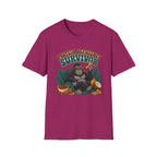 A heather magenta short-sleeve t-shirt with a graphic of a gorilla wearing sunglasses and holding a banana, surrounded by text that reads 'PROTEIN DEFICITY SURVIVOR' and tropical elements like leaves, a bowl of beans, and a coconut.