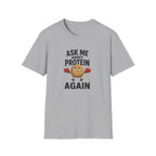 A light gray heather crewneck t-shirt featuring a graphic print of a cartoon protein powder bag character wearing red boxing gloves, with the text 'ASK ME ABOUT PROTEIN AGAIN' in black.
