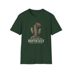 Forest green short-sleeve crewneck t-shirt featuring a graphic of a cactus with a flower and the text 'I'D RATHER BE DIFFICULT THAN EASY TO USE' printed on the front, displayed against a solid white background.