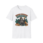 A white short-sleeve crewneck t-shirt featuring a retro-style graphic of a gorilla wearing sunglasses and holding a banana, surrounded by leaves and food items, with the text 'PROTEIN DEFICENCY SURVIVOR' above it.