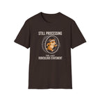 A dark brown short-sleeve t-shirt with a graphic of a cartoon chipmunk inside a running wheel, with the text 'STILL PROCESSING' above and 'THE LAST RIDICULOUS STATEMENT' below, displayed on a solid white background.
