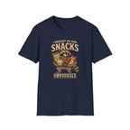 A navy blue short-sleeve crewneck t-shirt featuring a vintage-style graphic of a raccoon holding a basket of snacks with the text 'I BROUGHT MY OWN SNACKS OBVIOUSLY.' printed on the front.