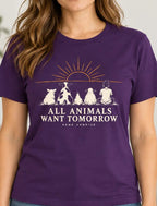 Woman wearing a purple graphic T-shirt featuring a pig, cow, chicken, sheep and person sitting beneath a sunrise with the words “All Animals Want Tomorrow” and “Same Sunrise.”