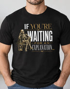 A man wearing a black graphic t-shirt with a gold and white skeleton design and the text 'IF YOU'RE WAITING FOR AN EXPLANATION.