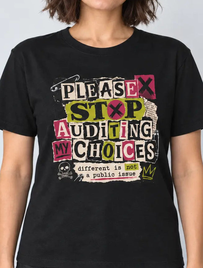 A woman wearing a black graphic t-shirt with the text 'PLEASE STOP AUDITING MY CHOICES' in a colorful, distressed collage style, paired with dark gray jeans, against a light gray background.