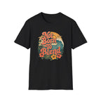 A black short-sleeve crewneck t-shirt featuring a retro circular graphic on the chest with the text 'Not Born To Blend' in coral orange, surrounded by a sunset, waves, and tropical flowers.