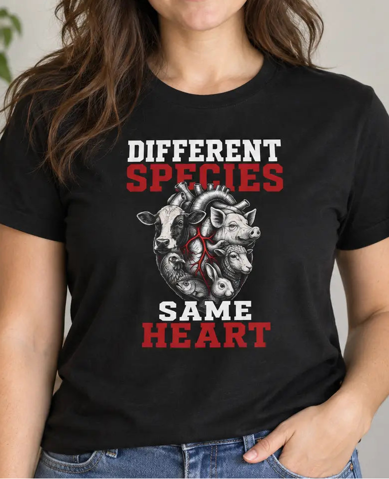 A woman wearing a black graphic t-shirt with the text 'DIFFERENT SPECIES SAME HEART' and an illustration of a horse and dog with a ribbon, posed in a brightly lit indoor setting.