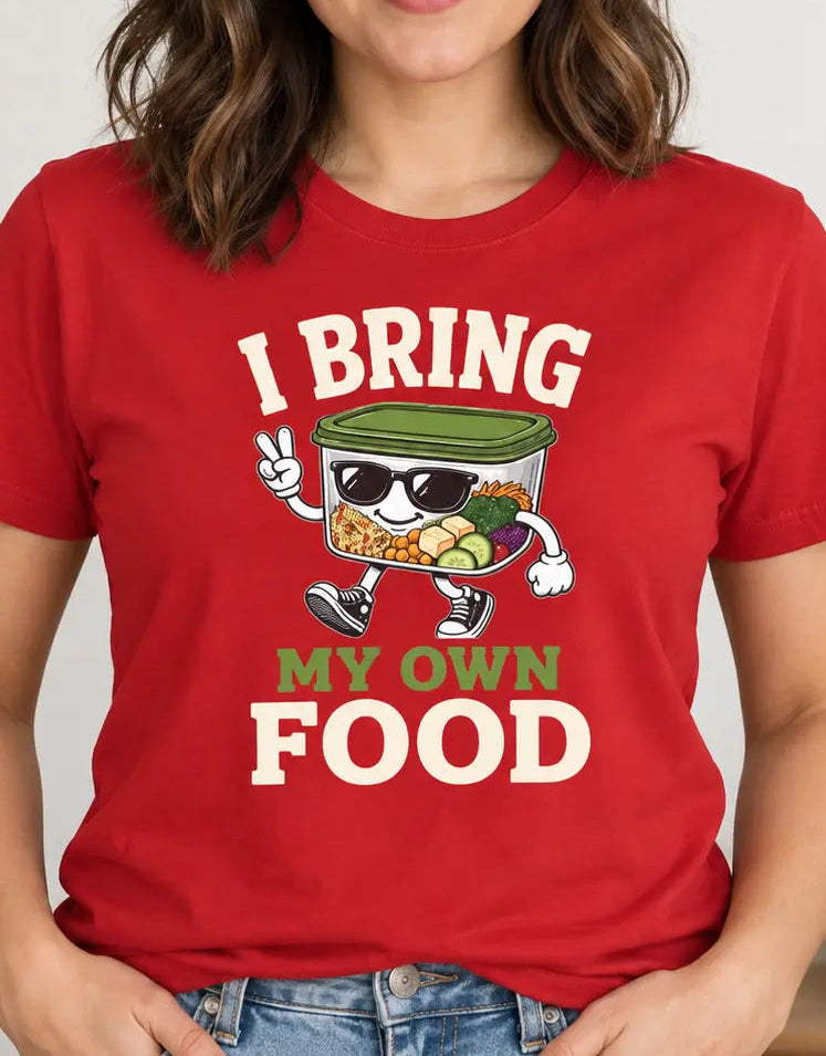 A woman wearing a red graphic t-shirt with a cartoon canned food character and the text 'I BRING MY OWN FOOD'.