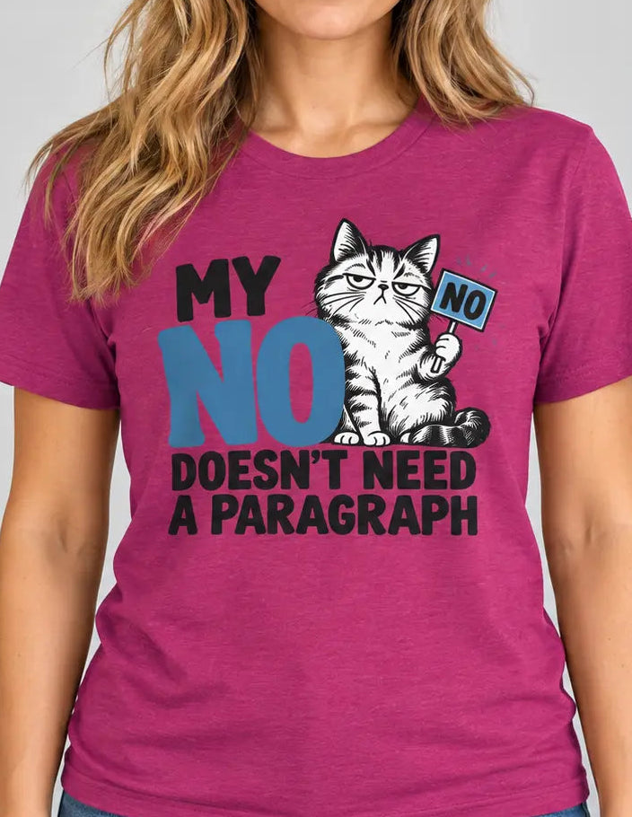 Front-facing lifestyle photo of a woman standing upright with her arms relaxed at her sides, wearing a heather magenta T-shirt with a grumpy cat graphic and the slogan “MY NO DOESN’T NEED A PARAGRAPH” in black and blue lettering. She is wearing blue jeans and photographed against a clean light gray background.