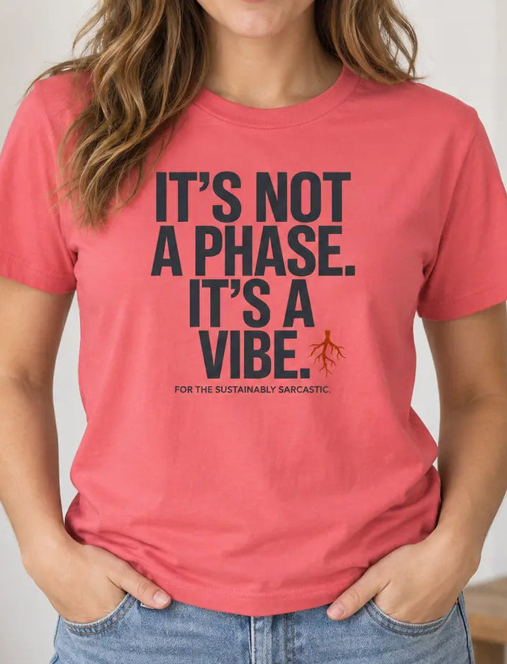 A woman wearing a coral pink graphic t-shirt with the text 'IT'S NOT A PHASE. IT'S A VIBE.