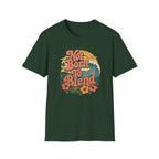 A dark green short-sleeve crewneck t-shirt featuring a retro-style graphic on the chest with the text 'Not Born To Blend' in orange, accompanied by a wave, palm tree, and hibiscus flowers.