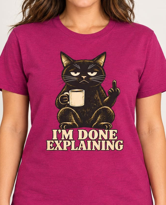 woman wearing a Pink t-shirt of a Black cat holding a coffee mug and raising its middle finger above the words “I’m Done Explaining” in bold cream vintage lettering.
