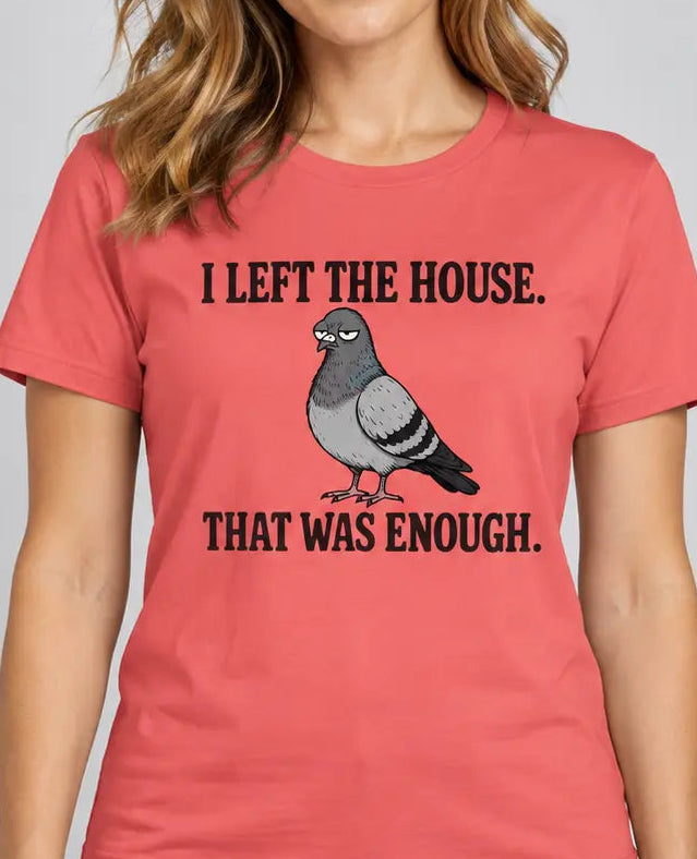 A woman wearing a coral pink t-shirt with a humorous graphic print. The print features the text 'I LEFT THE HOUSE.