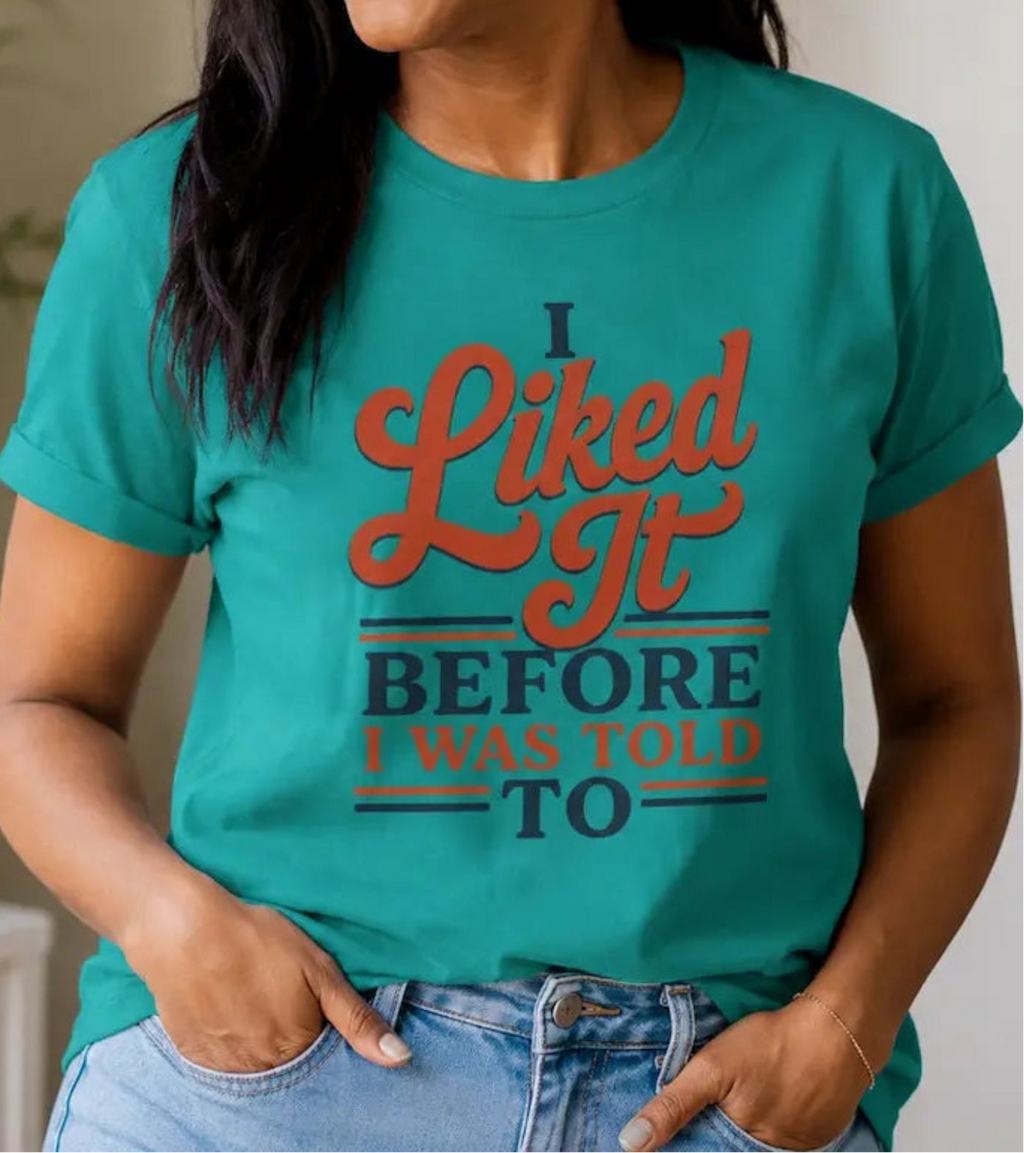 Woman wearing a green t-shirt with the  words 'i liked it before i was told to'