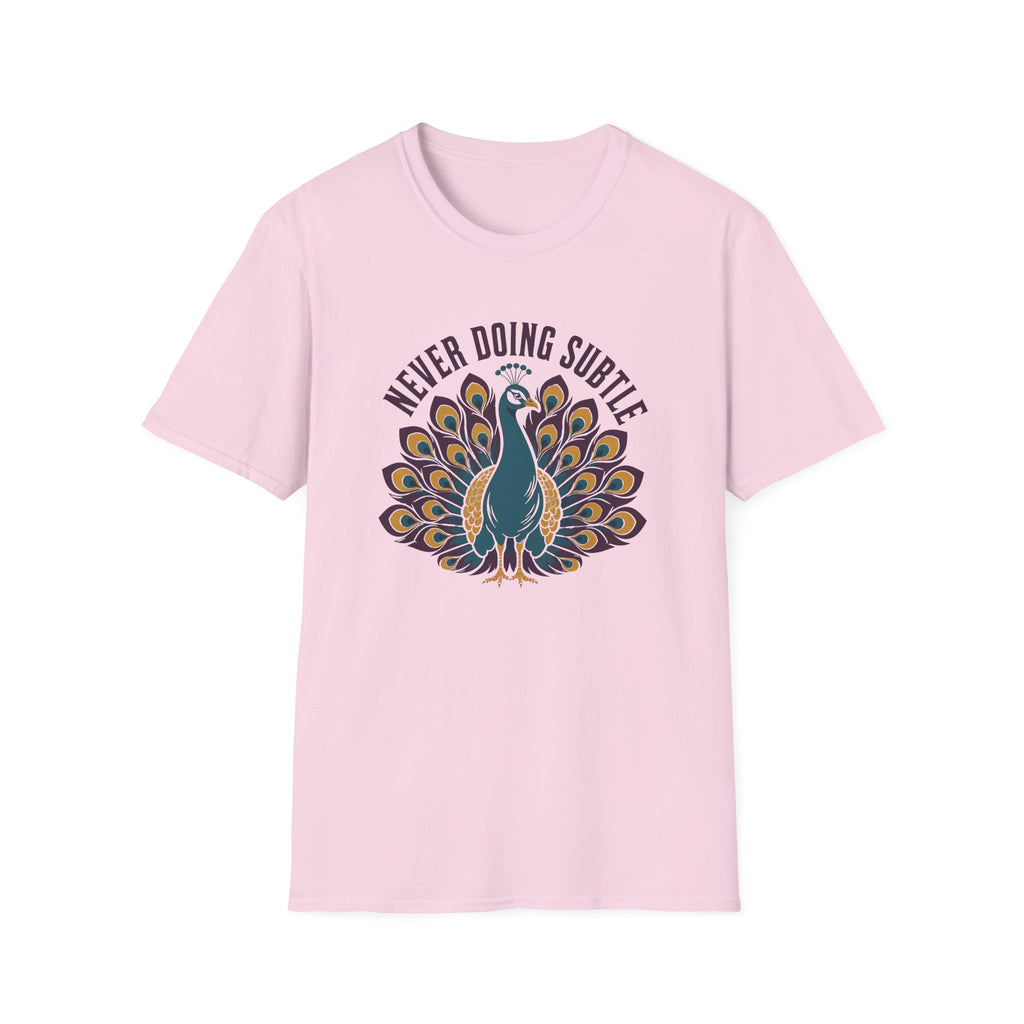 A light pink short-sleeve crewneck t-shirt featuring a graphic of a teal peacock with its tail fanned out, surrounded by the text 'NEVER DOING SUBTLE' in a dark arched font.