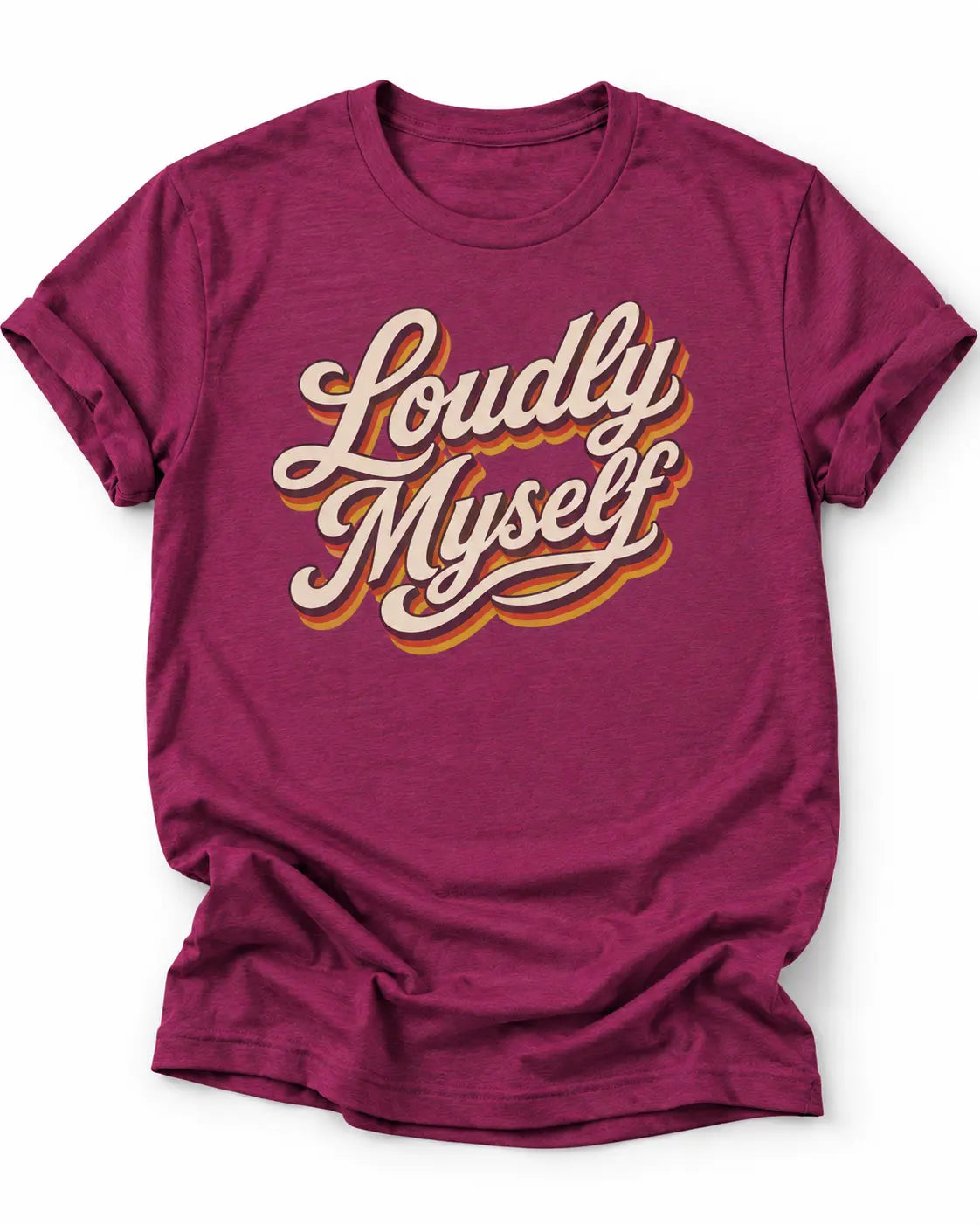 Magenta short-sleeve graphic t-shirt with the words 'Loudly Myself' in a cream and gold retro script, paired with blue jeans, sitting in a brightly lit indoor setting.