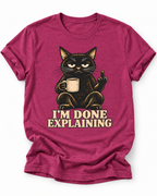 Pink t-shirt of a Black cat holding a coffee mug and raising its middle finger above the words “I’m Done Explaining” in bold cream vintage 