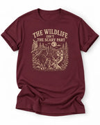 Maroon t-shirt with nature graphic of animals and halloween characters walking up a path and text 'the wildlife isn;t the scary part