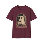 A maroon short-sleeve crewneck t-shirt featuring a vintage-style Halloween graphic of a ghostly figure with a large black eye next to a carved pumpkin, with the text 'CREEPY BUT KIND' printed below.