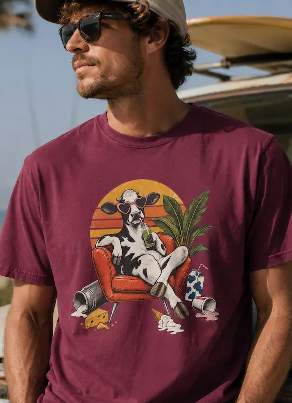 Man wearing a maroon tee with relaxing cow graphic and dairy products discarded at its feet