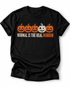 Black Graphic T-shirt design featuring five jack-o’-lanterns, with one white mismatched pumpkin standing out from four orange pumpkins, above the words “Normal Is the Real Horror.”