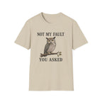 A beige short-sleeve crewneck t-shirt featuring a graphic of a brown owl perched on a branch with the text 'NOT MY FAULT YOU ASKED' in black.