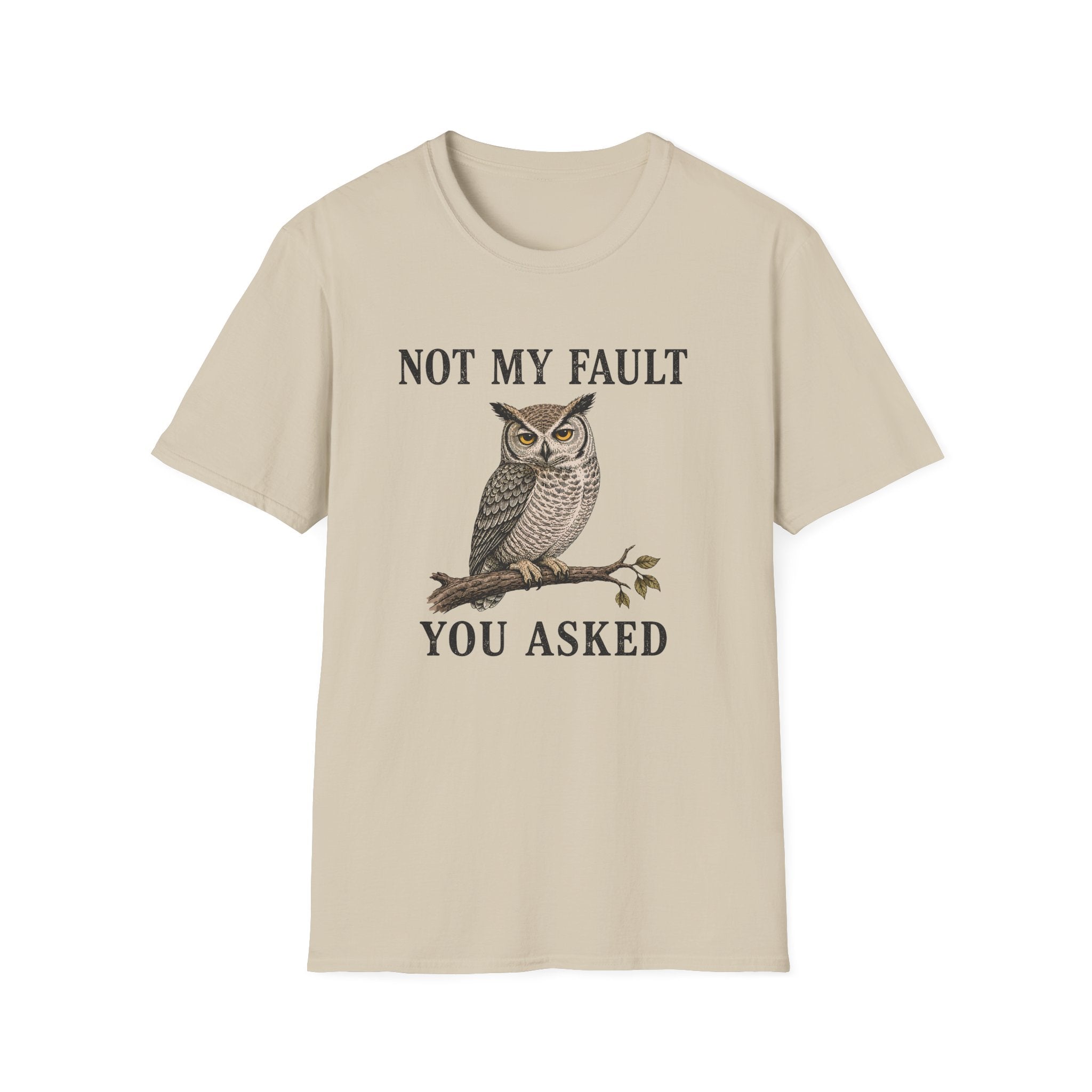 A beige short-sleeve crewneck t-shirt featuring a graphic of a brown owl perched on a branch with the text 'NOT MY FAULT YOU ASKED' in black.