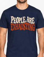 Man wearing a Navy Blue t-shirt with Distressed retro typography design reading “People Are Exhausting” in cream and burnt orange with drooping, tired-looking letterforms.