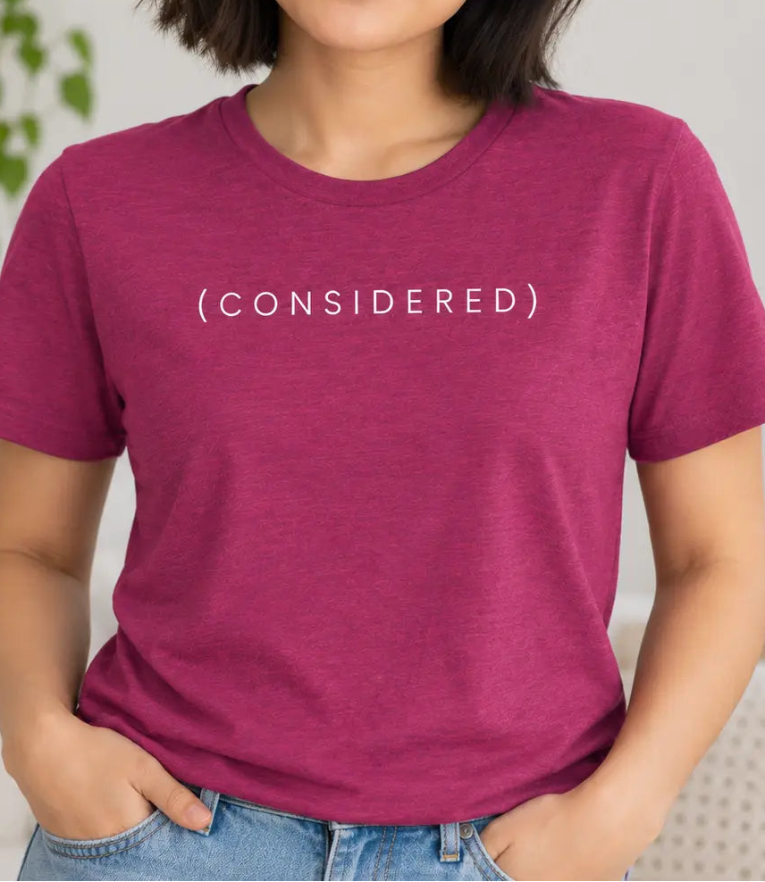 Woman wearing a hot pink tee with the word (onsidered)