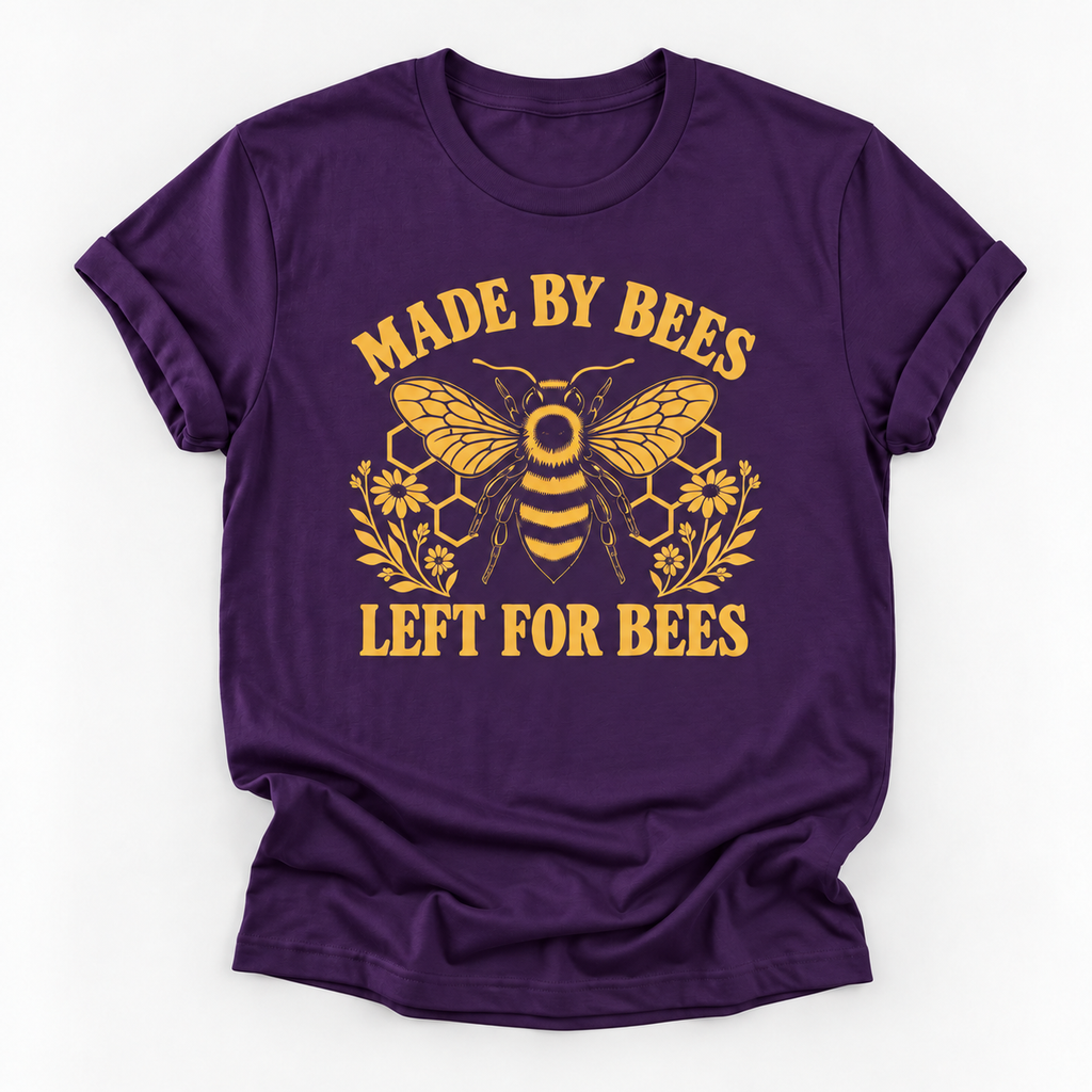 A purple short-sleeve crewneck t-shirt with a yellow graphic of a bee, honeycomb, and flowers, with the text 'MADE BY BEES LEFT FOR BEES' printed on the front, shown against a plain white background.