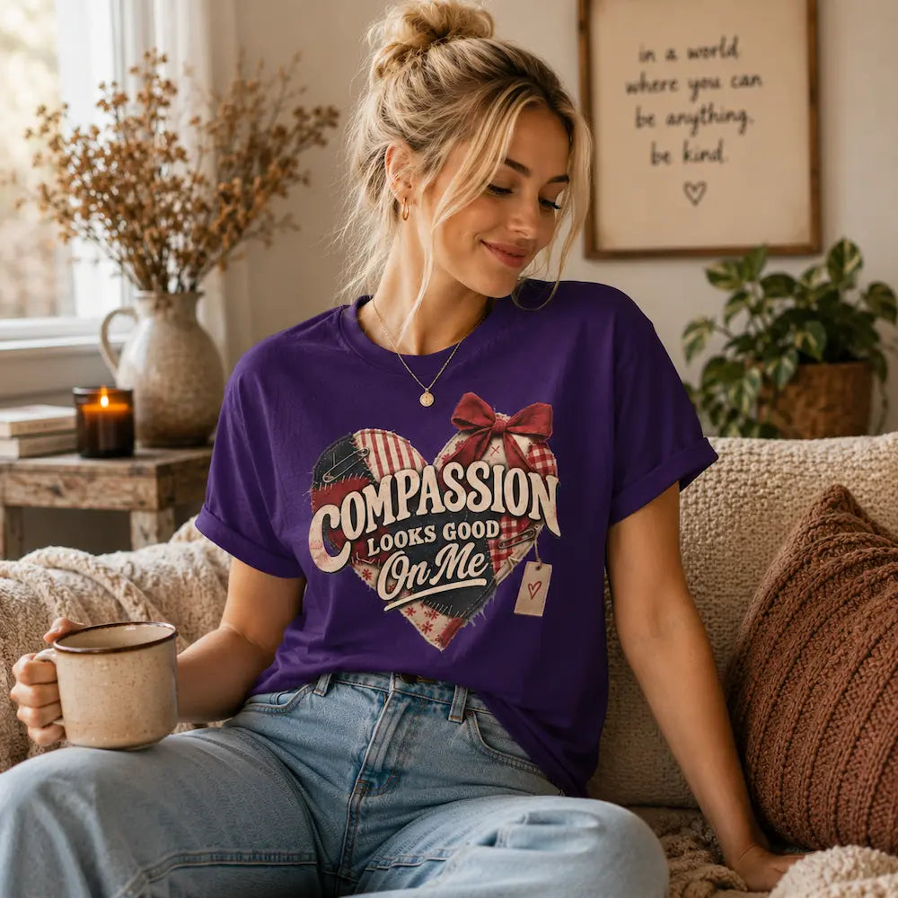 Purple tee with woman on a sofa and graphic of a heart with text ' compassion looks good on me'