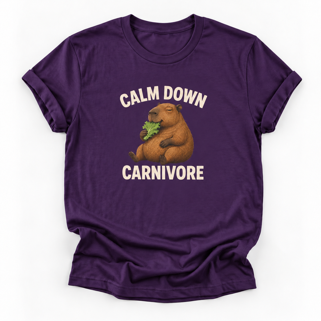 A purple short-sleeve crewneck t-shirt featuring a cartoon capybara eating green leaves with the text 'CALM DOWN CARNIVORE' printed in white above and below the graphic.