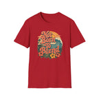 A red short-sleeve crewneck t-shirt featuring a retro-style circular graphic on the chest with the text 'Not Born To Blend' in orange, surrounded by a wave, sunset, and tropical flowers.
