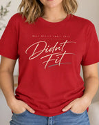 A woman wearing a red graphic t-shirt with the text 'Didnt Fit' in white and gray script, standing in a brightly lit, modern living room.