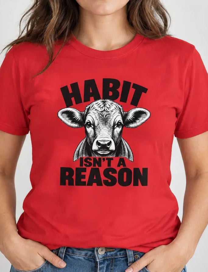 A woman wearing a red graphic t-shirt with a black and white cow illustration and the text 'HABIT ISN'T A REASON'.