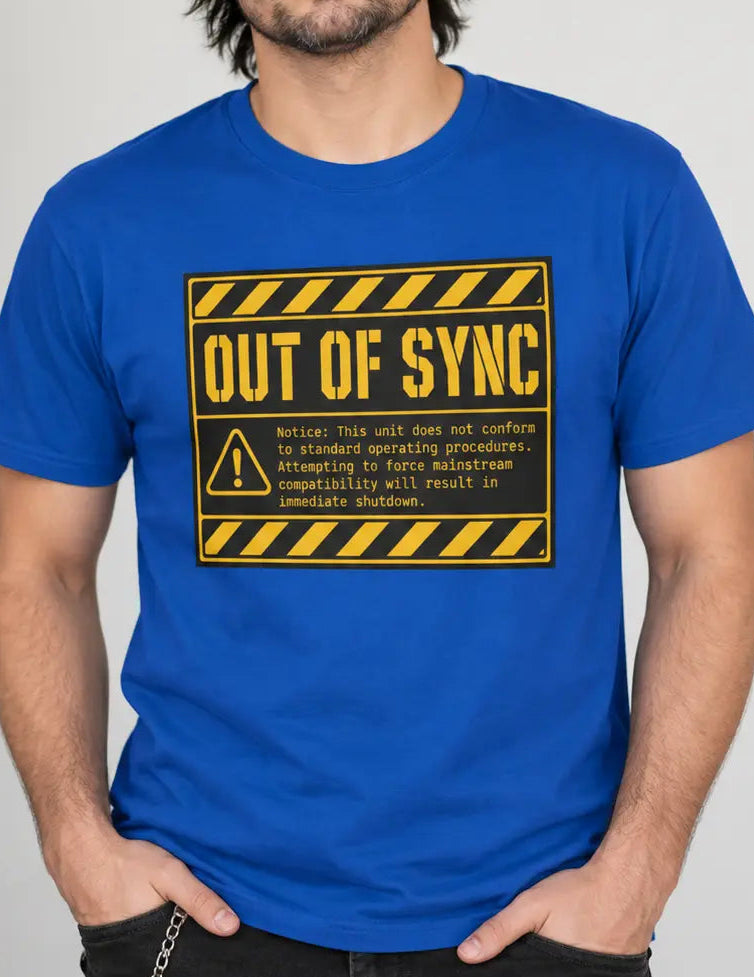 A man wearing a bright blue crewneck t-shirt with a yellow and black 'OUT OF SYNC' warning label graphic on the chest, standing against a light gray wall.