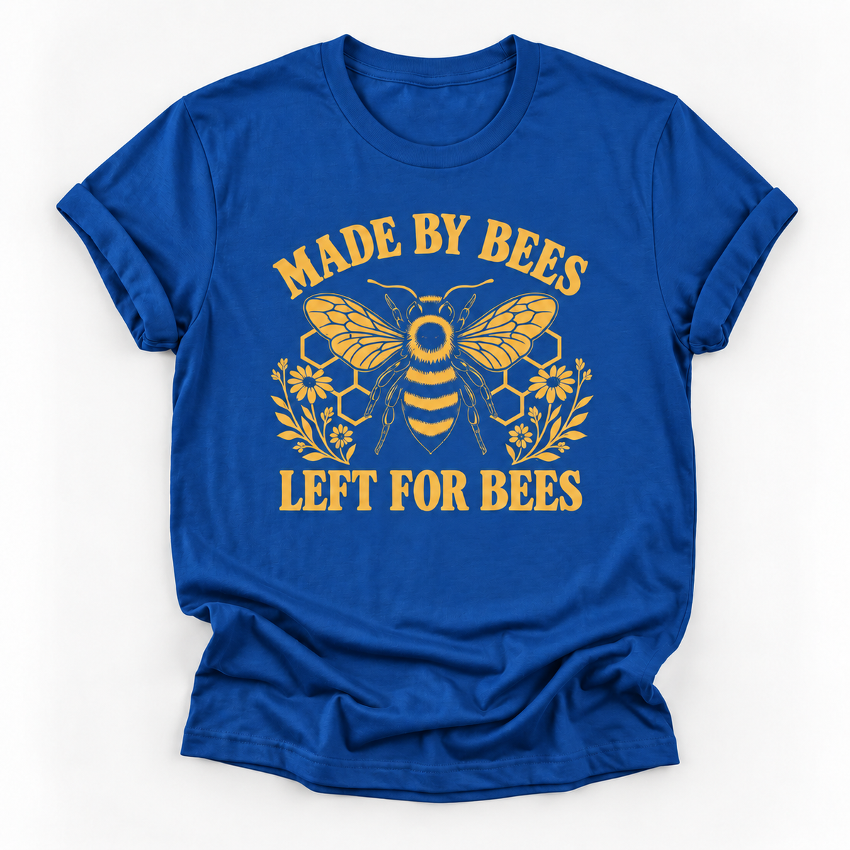 A royal blue short-sleeve t-shirt with a yellow graphic print featuring a bee, honeycomb, flowers, and the text 'MADE BY BEES LEFT FOR BEES' on a white background.