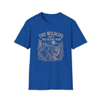 A royal blue short-sleeve crewneck t-shirt with a vintage-style cream graphic on the front. The graphic features the text 'THE WILDLIFE ISN'T THE SCARY PART' above an illustration of a forest scene with a deer, raccoon, owl, and a moon with stars.