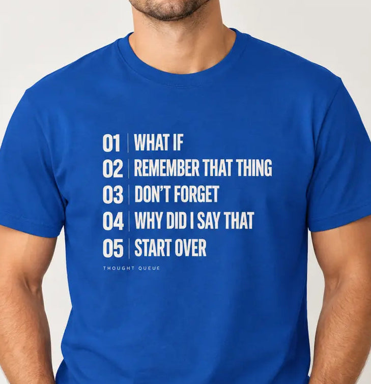 Man wearing royal blue graphic T-shirts featuring a cream numbered “Thought Queue” list with the phrases “What If,” “Remember That Thing,” “Don’t Forget,” “Why Did I Say That,” and “Start Over.”
