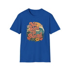 A royal blue short-sleeve crewneck t-shirt featuring a retro-style circular graphic on the chest with the text 'Not Born To Blend' in orange, surrounded by a sunset, waves, and tropical flowers.