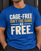 A man wearing a bright blue graphic t-shirt with the text 'CAGE-FREE ISN'T THE SAME AS FREE.' printed in white and yellow, leaning against a dark wooden door.