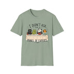 A sage green short-sleeve crewneck t-shirt featuring a cartoon graphic of four animals (a cat, frog, panda, and turtle) sitting at a table with the text 'I DIDN'T ASK FOR A PANEL OF EXPERTS.'.