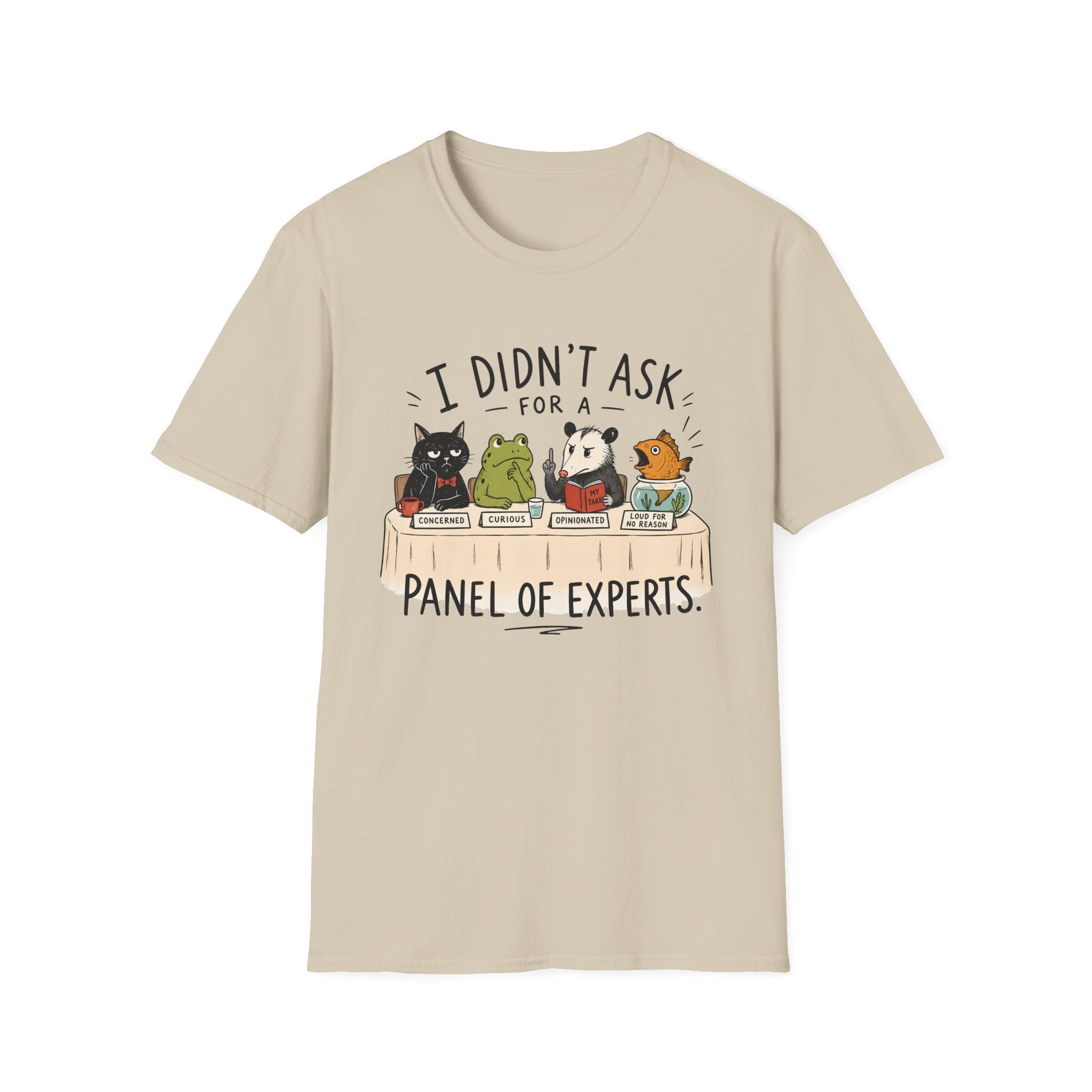 A beige short-sleeve crewneck t-shirt featuring a cartoon graphic of four animals (a cat, frog, panda, and turtle) sitting at a table with books, captioned with the text 'I DIDN'T ASK FOR A PANEL OF EXPERTS.'.