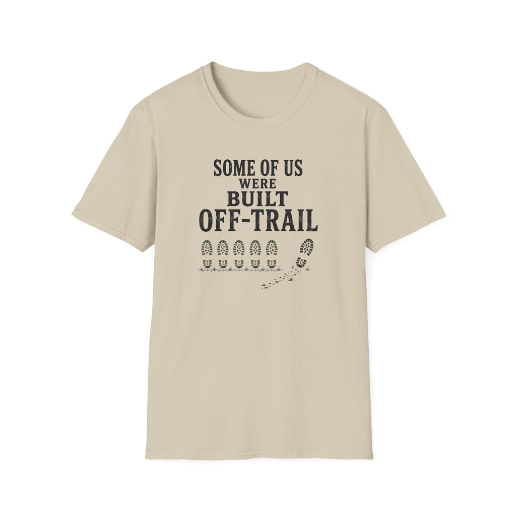 A light beige crewneck t-shirt with a black graphic print on the front that reads 'SOME OF US WERE BUILT OFF-TRAIL' above a trail footprint graphic, shown on a plain white background.
