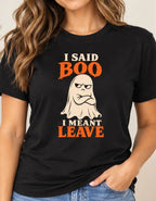 Woman wearing a black graphic T-shirt featuring a grumpy cream ghost with crossed arms and the words “I Said Boo I Meant Leave” in cream and orange lettering.