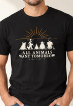 Man wearing a black graphic T-shirt featuring a pig, cow, chicken, sheep and person sitting beneath a sunrise with the words “All Animals Want Tomorrow” and “Same Sunrise.”