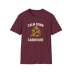 Maroon vegan short-sleeve crewneck t-shirt featuring a cartoon graphic of a brown groundhog holding green lettuce, with the text 'CALM DOWN CARNIVORE' printed in beige above and below the illustration.