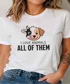 A woman wearing a white graphic t-shirt with a cartoon dog face and the text 'I LOVE ANIMALS ALL OF THEM' in black. She is also wearing blue jeans, standing in a brightly lit indoor setting.